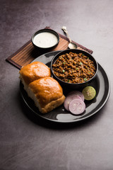 Kheema / keema Pav or Khima Paav is a spicy curry dish made up of minced chicken or lamb cooked with onion, tomatoes, served with buns. selective focus