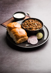 Kheema / keema Pav or Khima Paav is a spicy curry dish made up of minced chicken or lamb cooked with onion, tomatoes, served with buns. selective focus