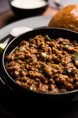 Kheema / keema Pav or Khima Paav is a spicy curry dish made up of minced chicken or lamb cooked with onion, tomatoes, served with buns. selective focus