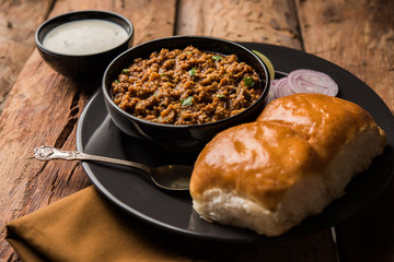 Kheema / keema Pav or Khima Paav is a spicy curry dish made up of minced chicken or lamb cooked with onion, tomatoes, served with buns. selective focus