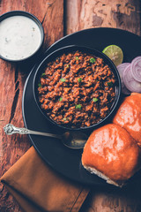 Kheema / keema Pav or Khima Paav is a spicy curry dish made up of minced chicken or lamb cooked with onion, tomatoes, served with buns. selective focus