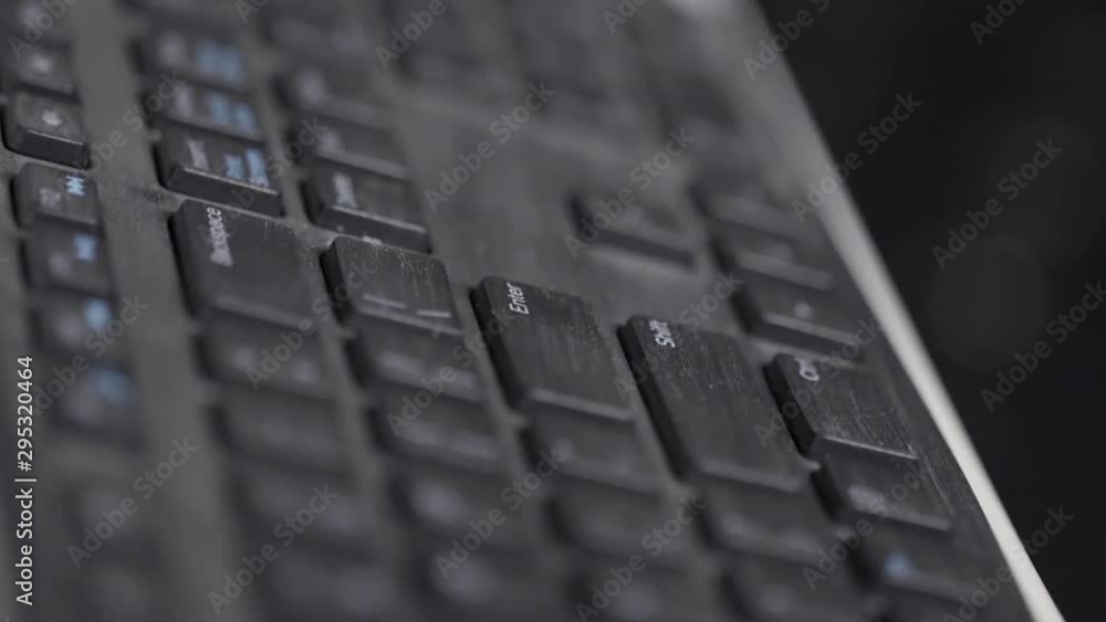 Poster close-up of finger over black laptop keys pressing enter button, computers and technologies concept.