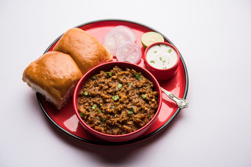 Kheema / keema Pav or Khima Paav is a spicy curry dish made up of minced chicken or lamb cooked with onion, tomatoes, served with buns. selective focus