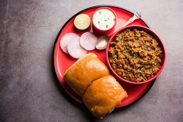 Kheema / keema Pav or Khima Paav is a spicy curry dish made up of minced chicken or lamb cooked with onion, tomatoes, served with buns. selective focus