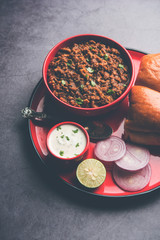 Kheema / keema Pav or Khima Paav is a spicy curry dish made up of minced chicken or lamb cooked with onion, tomatoes, served with buns. selective focus