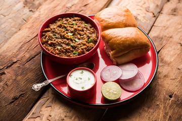 Kheema / keema Pav or Khima Paav is a spicy curry dish made up of minced chicken or lamb cooked with onion, tomatoes, served with buns. selective focus