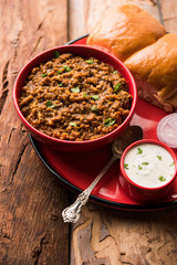 Kheema / keema Pav or Khima Paav is a spicy curry dish made up of minced chicken or lamb cooked with onion, tomatoes, served with buns. selective focus