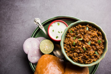 Kheema / keema Pav or Khima Paav is a spicy curry dish made up of minced chicken or lamb cooked with onion, tomatoes, served with buns. selective focus