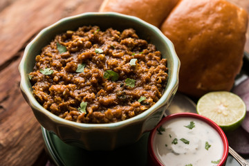 Kheema / keema Pav or Khima Paav is a spicy curry dish made up of minced chicken or lamb cooked with onion, tomatoes, served with buns. selective focus