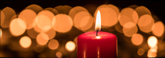 Burning candle in front of bokeh background