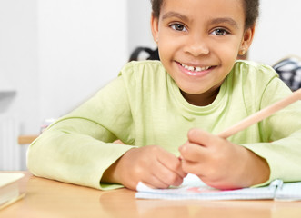 Naklejka premium Girl looking at camera and laughing while learning at school