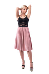 Classy young elegant blonde woman in evening wear with hands on hair looking down holding bun. Full body isolated on white background. 