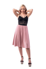 Tired blonde young woman having neck pain with both hands behind head looking down. Full body isolated on white background. 