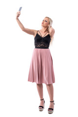 Elegant feminine young modern woman posing for selfie with smart phone. Full body isolated on white background. 