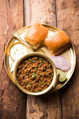 Kheema / keema Pav or Khima Paav is a spicy curry dish made up of minced chicken or lamb cooked with onion, tomatoes, served with buns. selective focus