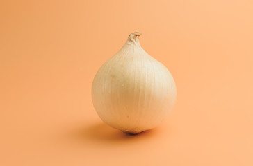 white onions in husks on a beige background, unpeeled sweet onions on the surface,onions in a minimalist style, vitamins, healthy eating concept.Copy space.