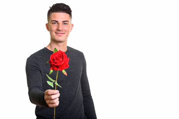 Studio shot of happy handsome man smiling while giving red rose