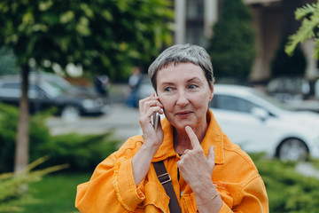 Fototapeta premium Portrait of a beautiful senior woman. Happy senior woman on the city streets using cellphone.