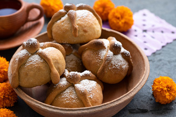 Mexican celebration, bread of death. Mexican parties with Dead bread and marigold flowers on gray stone background. Traditional Mexican Bread of the Dead Pan de Muerto .