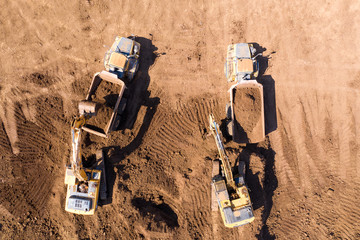 Vast Excavation site with an on going operation of Excavators loading soil onto Trucks, Aerial view.