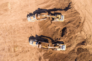 Vast Excavation site with an on going operation of Excavators loading soil onto Trucks, Aerial view.