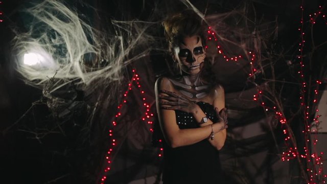 Portrait of Art makeup of skeleton on the feast of the dead. A terrible skeleton looks at the camera and rushes. Hallowin art party with people