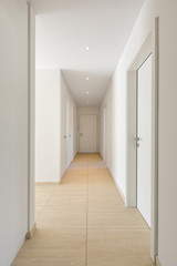 Corridor with travertine floor, white walls and built-in wardrobes