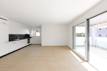 Fototapeta na wymiar Empty room with white walls, travertine floor and white kitchen and black marble