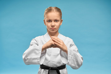 Karate girl with black belt practicing hands position.