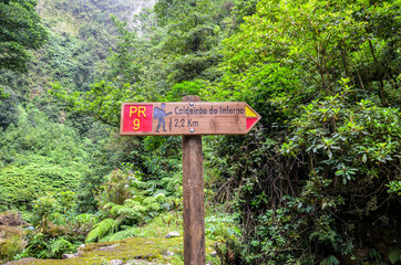 Information tourist sign giving directions and distances on a hiking trail Caldeirao de Inferno, Madeira island, Portugal. Levada walking on Portuguese island. Green forest in the background. Tourism