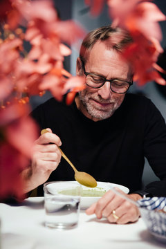 Ein Mann isst mit goldenem L&ouml;ffel eine Gem&uuml;sesuppe