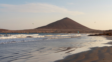 Fototapeta na wymiar Sunset at El Medano beach towards Montana Roja, a popular beach in the municipality of Granadilla de Abona for services and amenities, for the ideal swimming conditions, for windsurfing or kitesurfing
