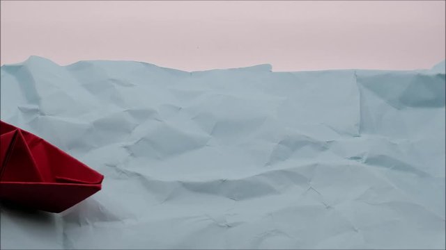 Red origami boat moving over blue paper sea