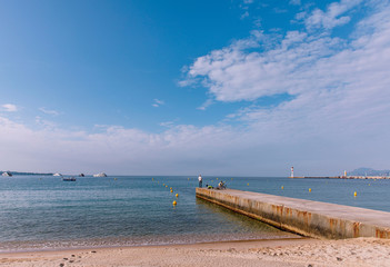 Obraz premium Men fishing a quiet beach close to the harbour of Cannes at the French Riviera, the Cote d'Azur, France