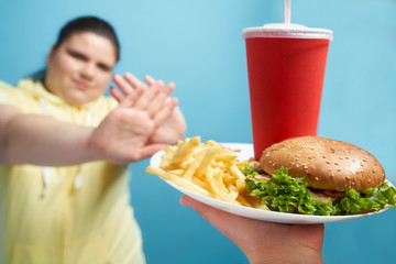 Overweight female denying fast food in her healthy lifestyle