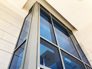 Obraz premium Facade of modern building with rectangular turquoise glass bay windows front view.