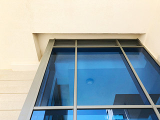 Facade of modern building with rectangular turquoise glass bay windows front view.