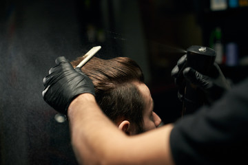 Crop of barber hands making new haircut for male client - obrazy, fototapety, plakaty