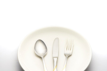 fork and spoon lay on white plate on white background