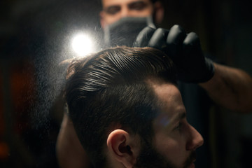 Close up of man's hair combing by barber in black gloves