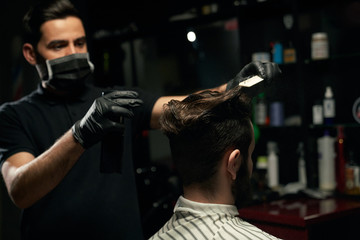 Male professional barber doing hair styling to handsome guy