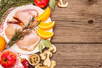 Raw chicken boneless meat with herbs and fruits on plate. Cooking at Christmas time or Thanksgiving Day
