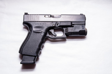 A black semi automatic 9mm pistol with an attached flashlight under the muzzle and an extended...