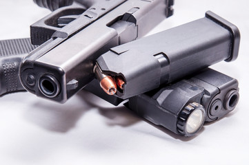 Two black semi automatic 9mm pistols with a loaded pistol magazine along with ammunition on a white background