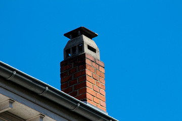 Tiled roof with an old chimney against a blue sky