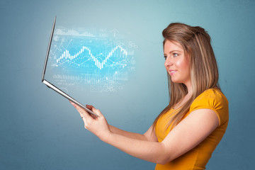 Woman holding laptop projecting financial information, diagrams and charts