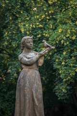 Fototapeta na wymiar Public park stone statue Of Girl With A Pigeon. Prague, Czech republic