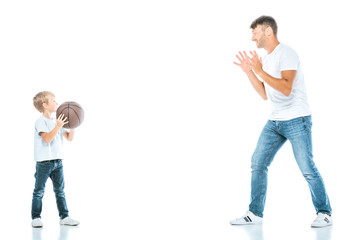 side view of handsome father playing basketball with son on white