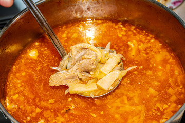 Red borsch in a saucepan with cabbage and fat, meat in a soup ladle.