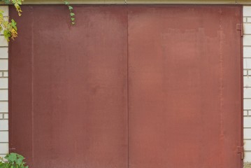 large brown closed metal gate on a brick wall of a garage